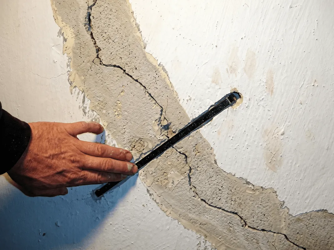 A wall with a large crack is being inspected by a professional in Springfield, MO